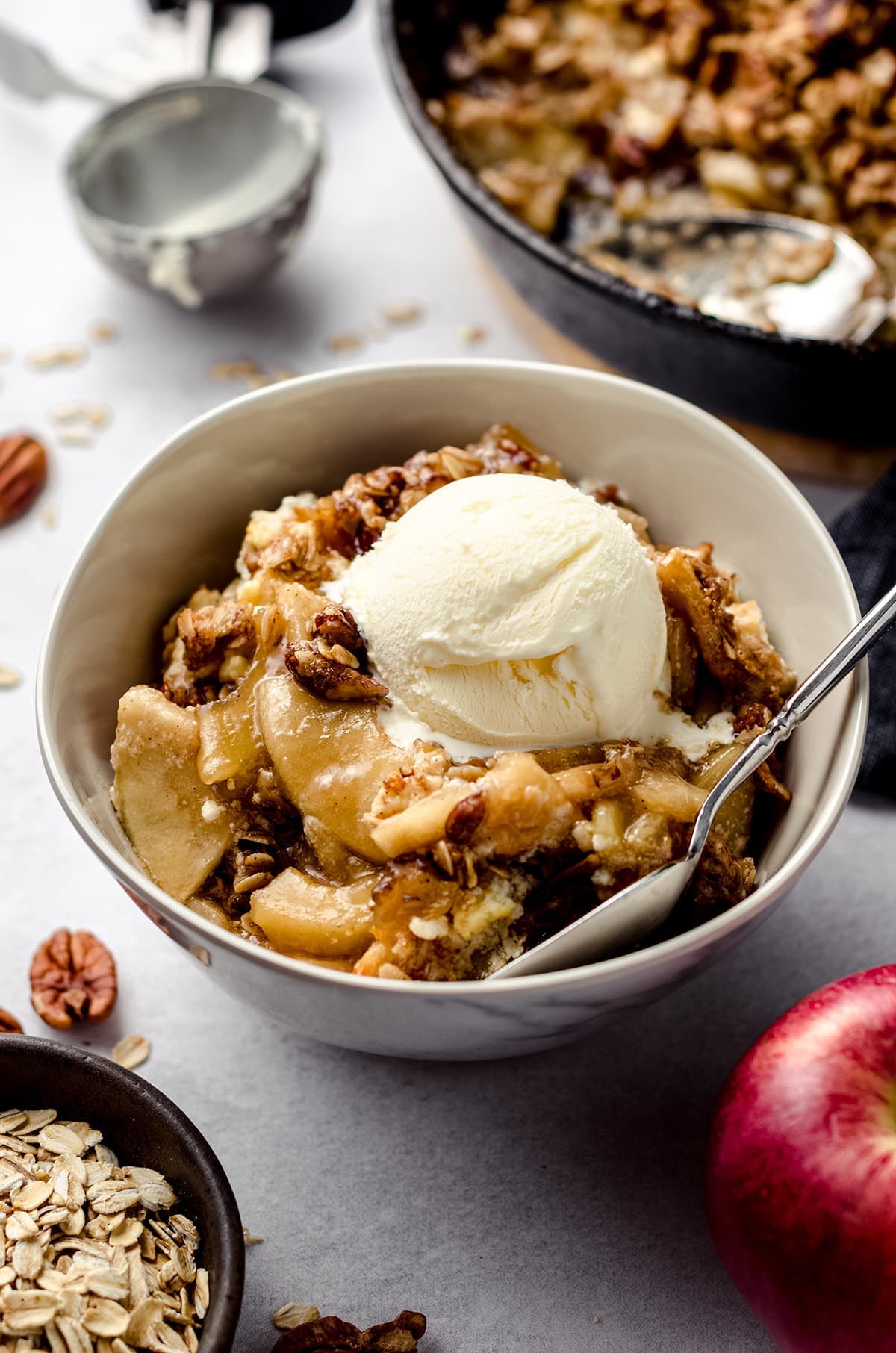 warm apple crisp in a bowl with a scoop of vanilla ice cream