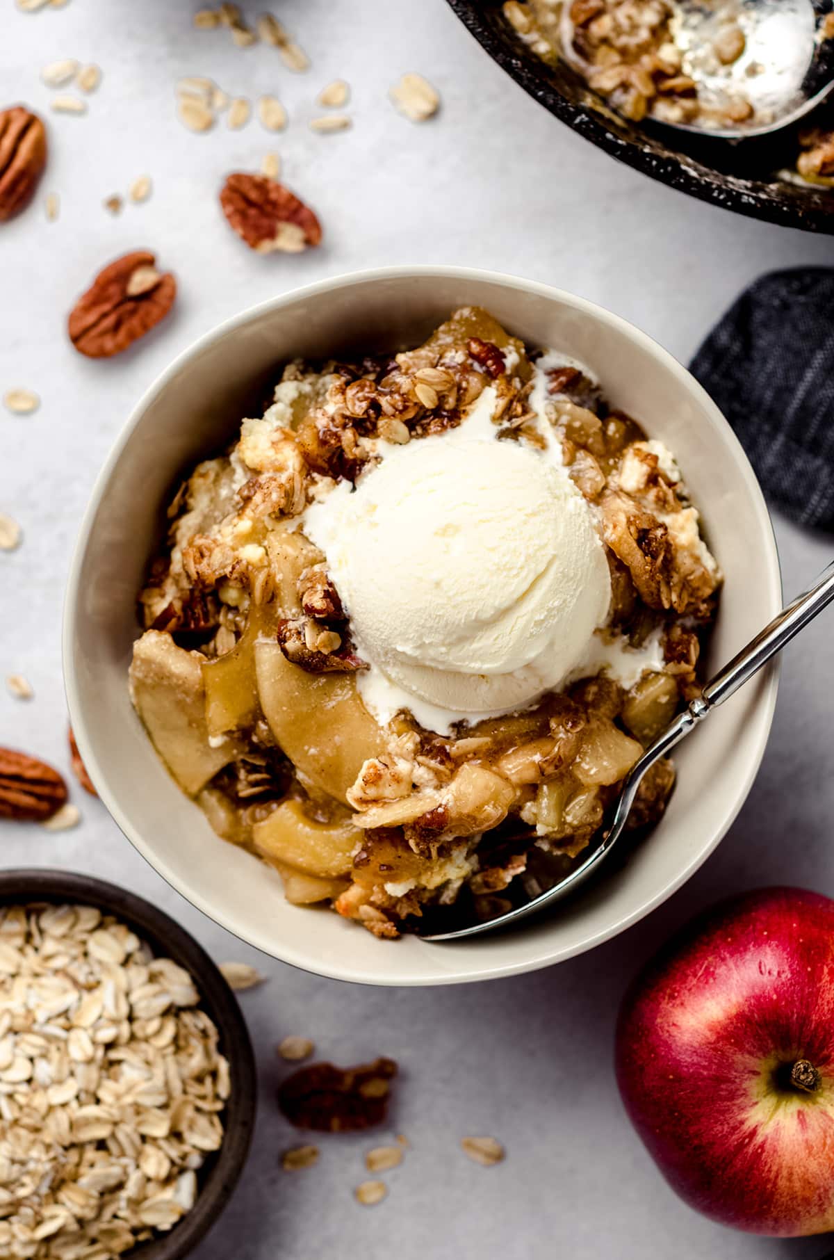 aerial photo of warm apple crisp in a bowl with a scoop of vanilla ice cream