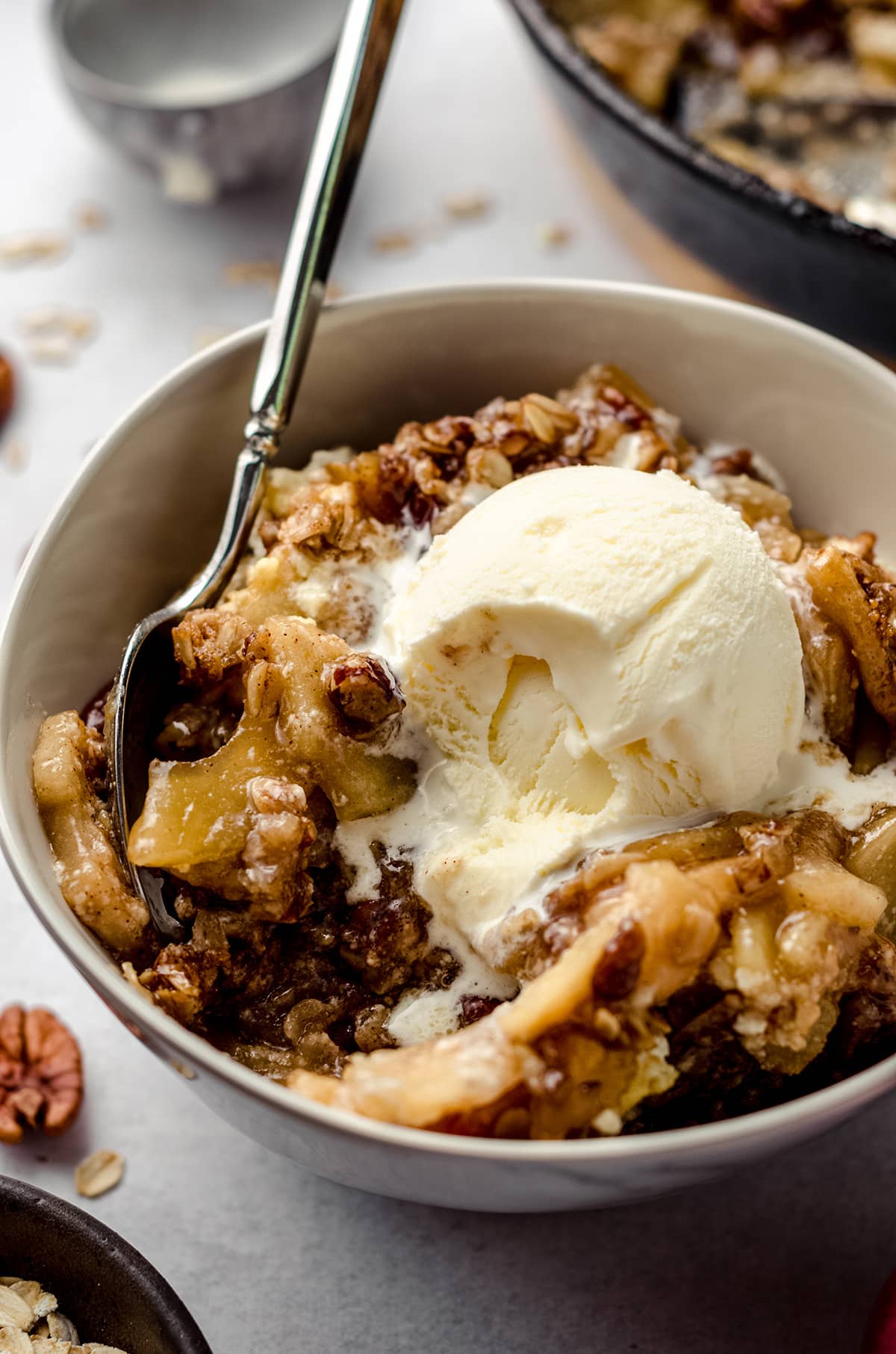 warm apple crisp in a bowl with a scoop of melting vanilla ice cream
