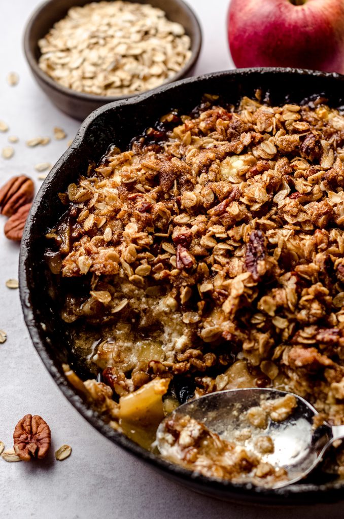 warm apple crisp in a skillet and a spoon