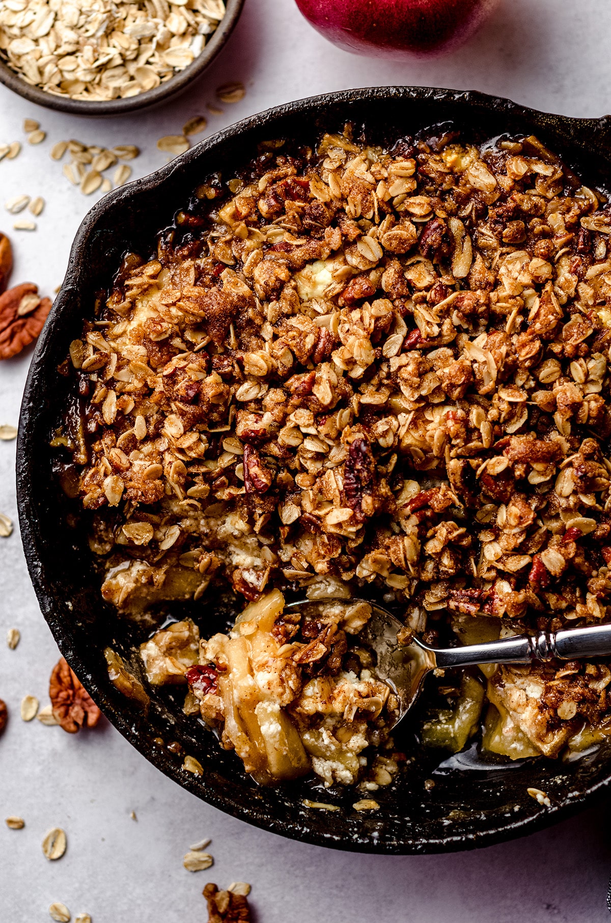 warm apple crisp in a skillet and a spoon