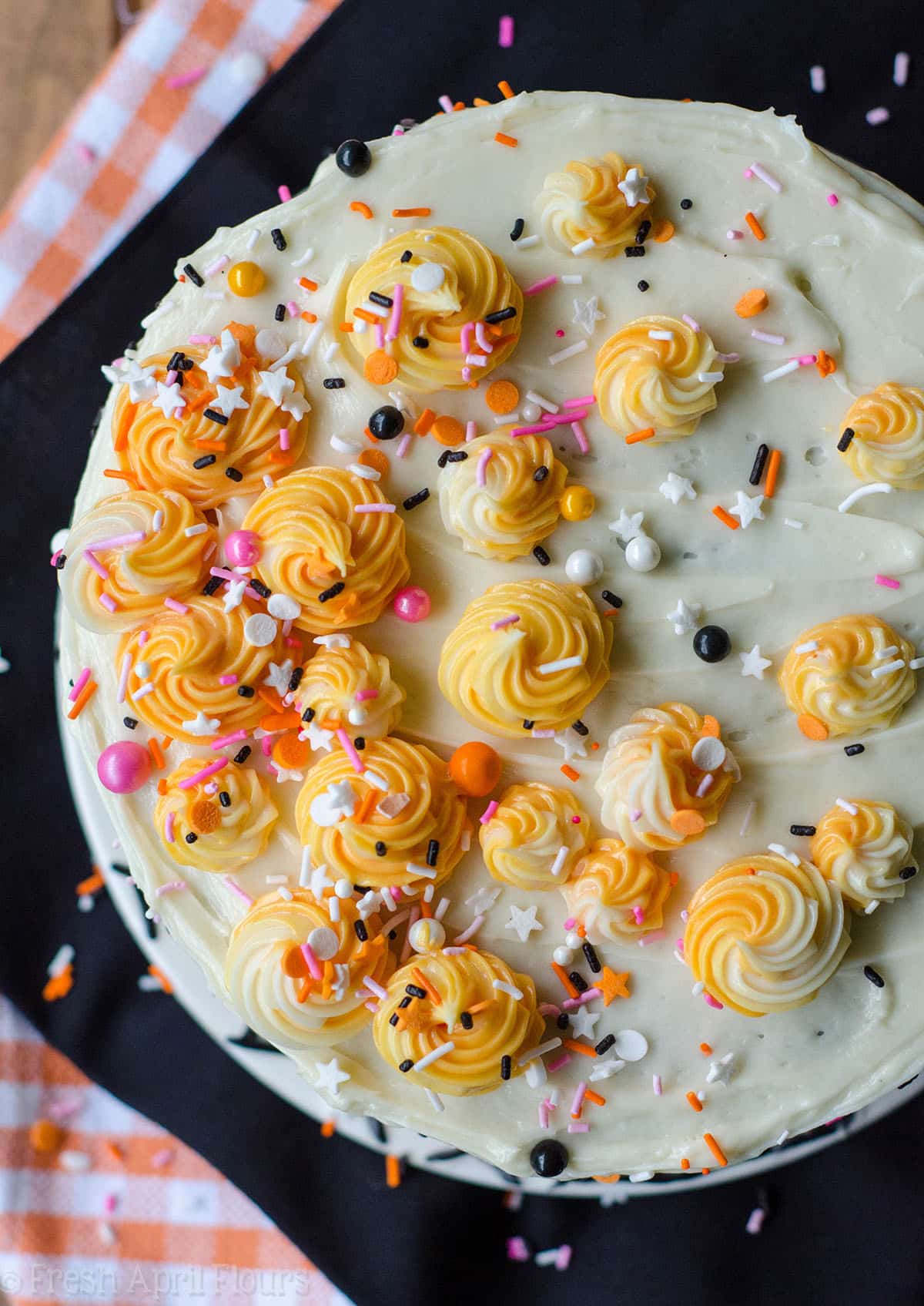 aerial photo of black layer cake with orange and pink sprinkles 