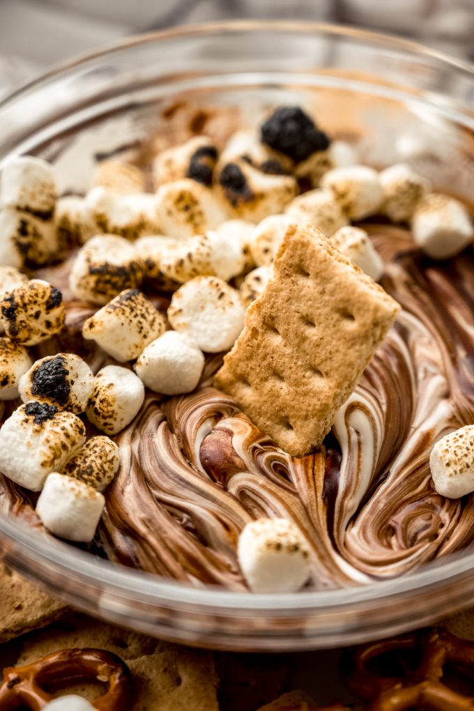 A graham cracker in a bowl of s'mores dip.