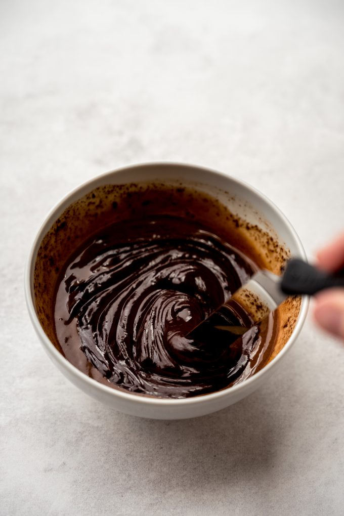 Someone is using a small offset spatula to stir a mixture to make chocolate ganache.