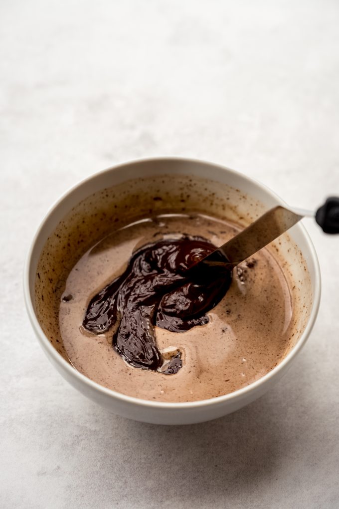 Someone is using a small offset spatula to stir a mixture to make chocolate ganache.