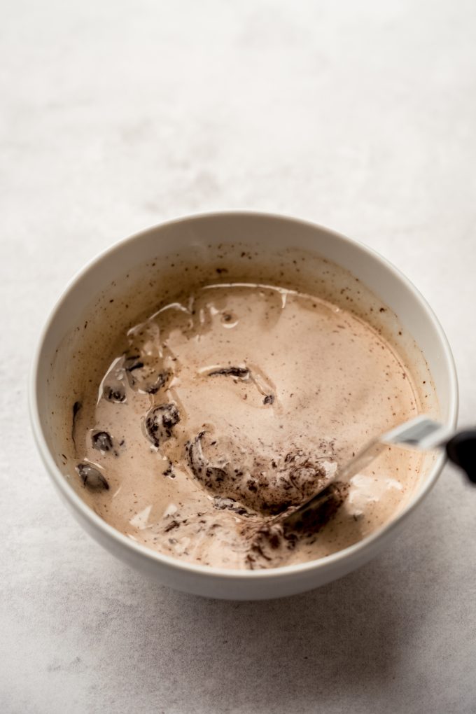 Someone is using a small offset spatula to stir a mixture to make chocolate ganache.