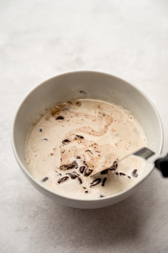Someone is using a small offset spatula to stir a mixture to make chocolate ganache.