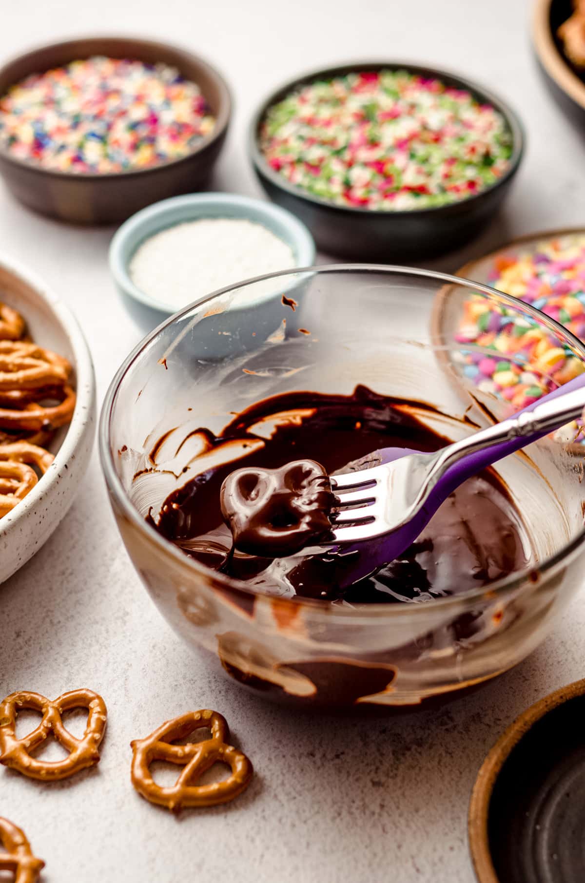 using a fork to dip mini pretzels in melted chocolate