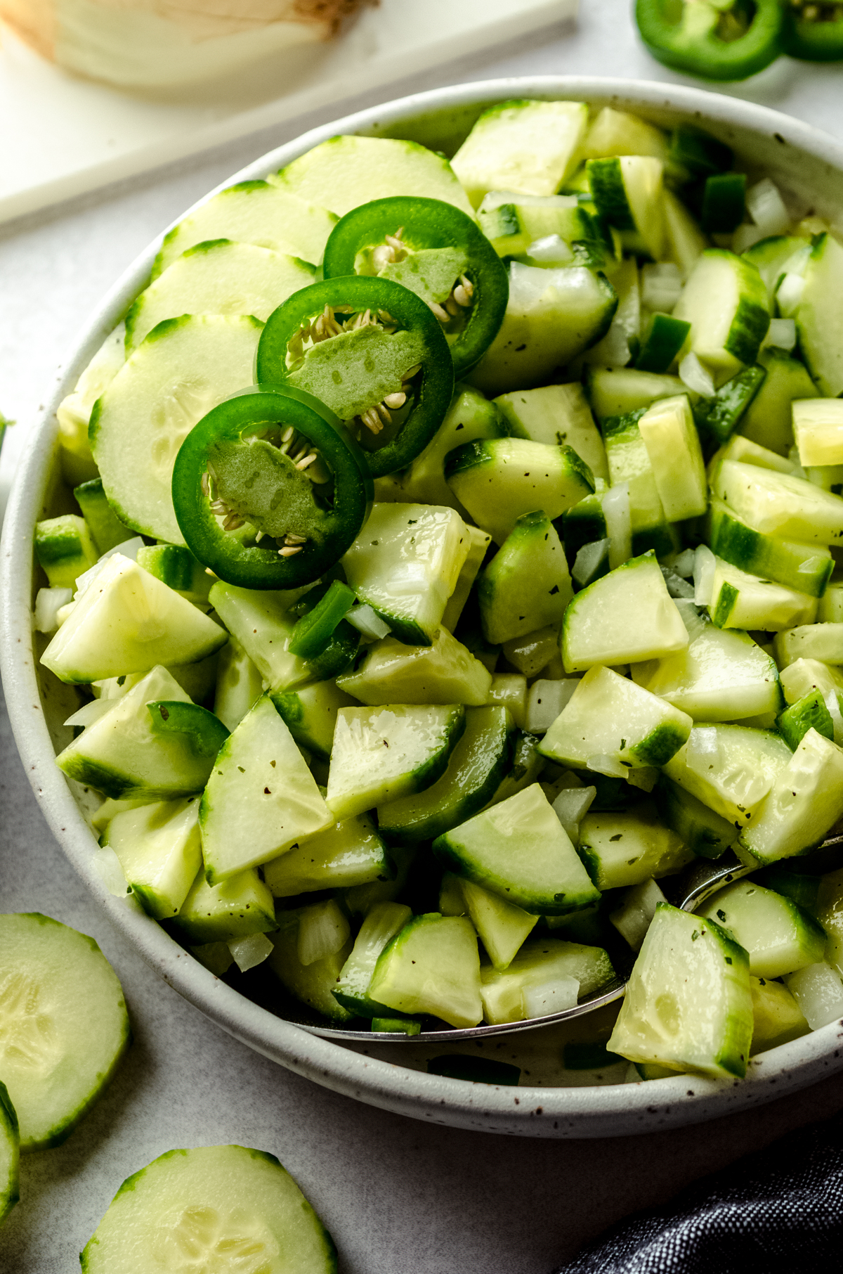 Zesty cucumber salad in a bowl with slices of jalapeño peppers on top.