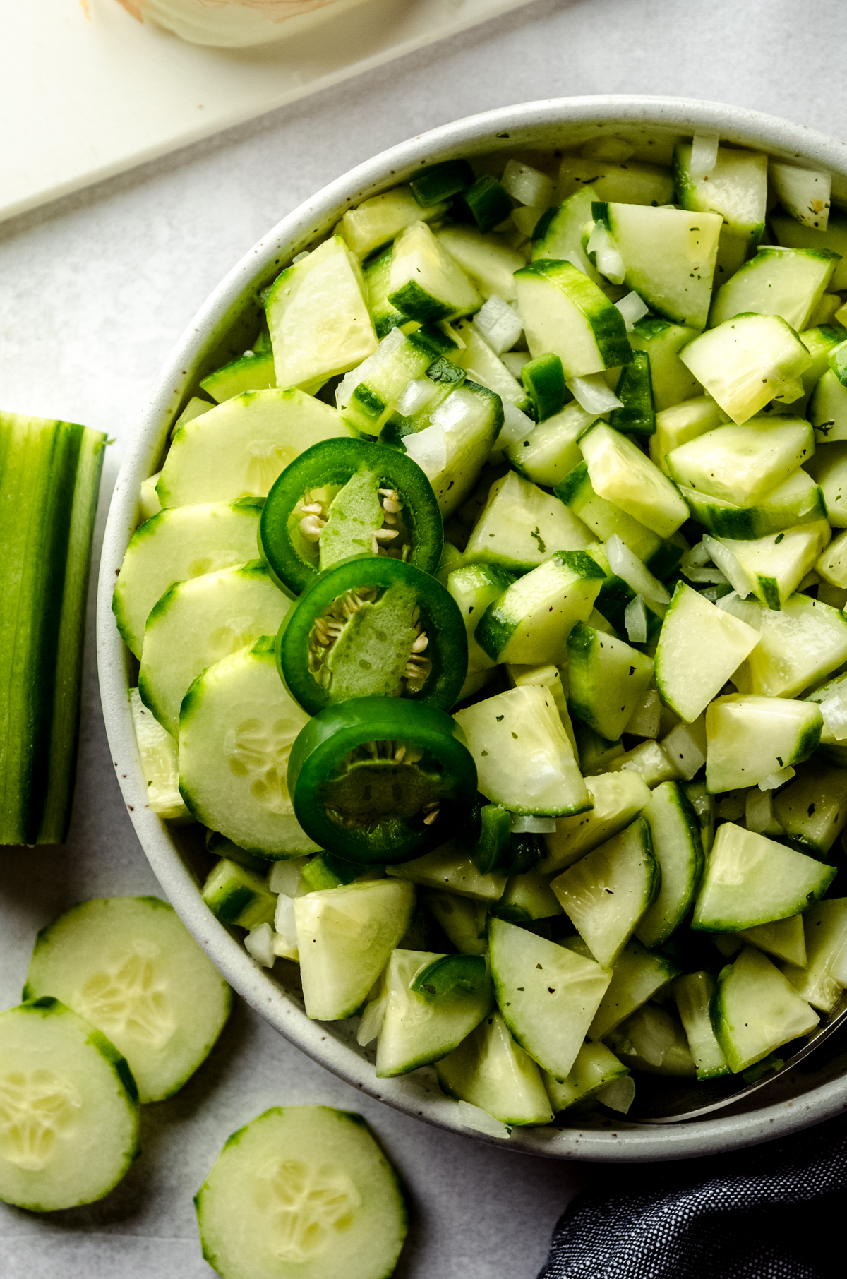 Aerial photo of cucumber salad in a bowl with slices of jalapeño peppers on top.