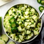 Aerial photo of cucumber salad in a bowl with slices of jalapeño peppers on top.