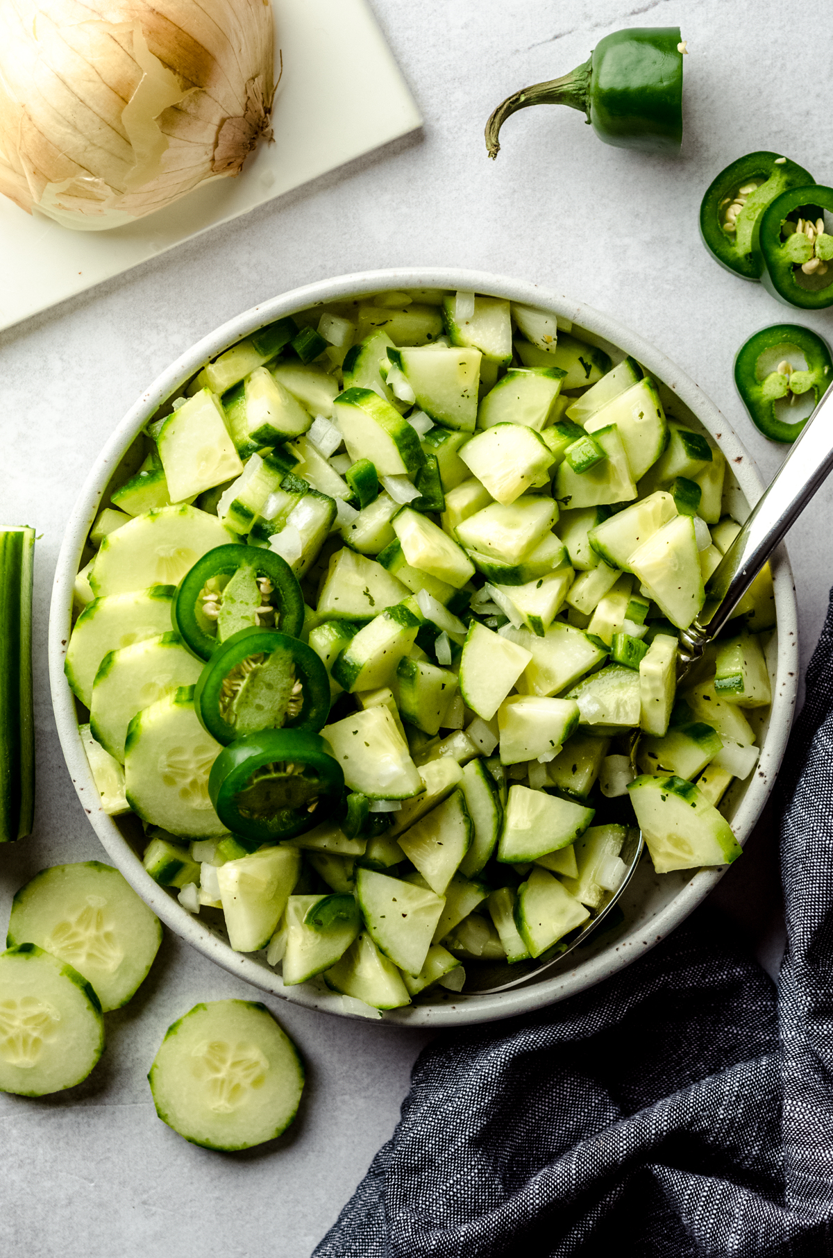 Aerial photo of cucumber salad in a bowl with slices of jalapeño peppers on top.