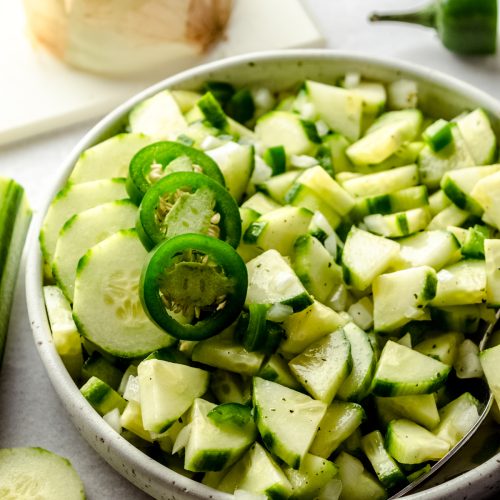 Zesty cucumber salad in a bowl with slices of jalapeño peppers on top.