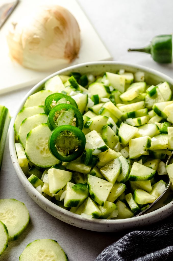 Zesty cucumber salad in a bowl with slices of jalapeño peppers on top.