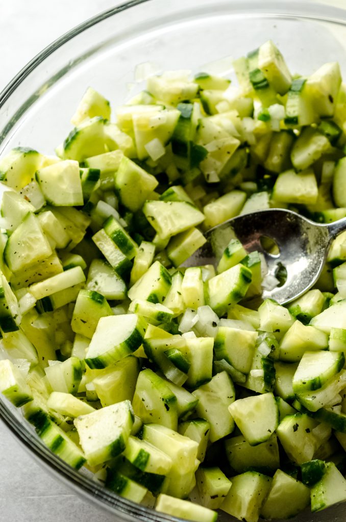 Cucumber salad in a bowl with a spoon.