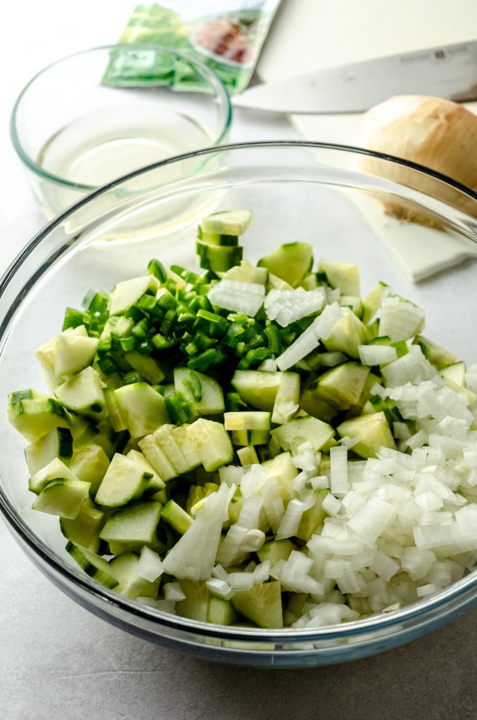 Chopped cucumbers in a bowl with a packet of ranch dressing sprinkled on top.