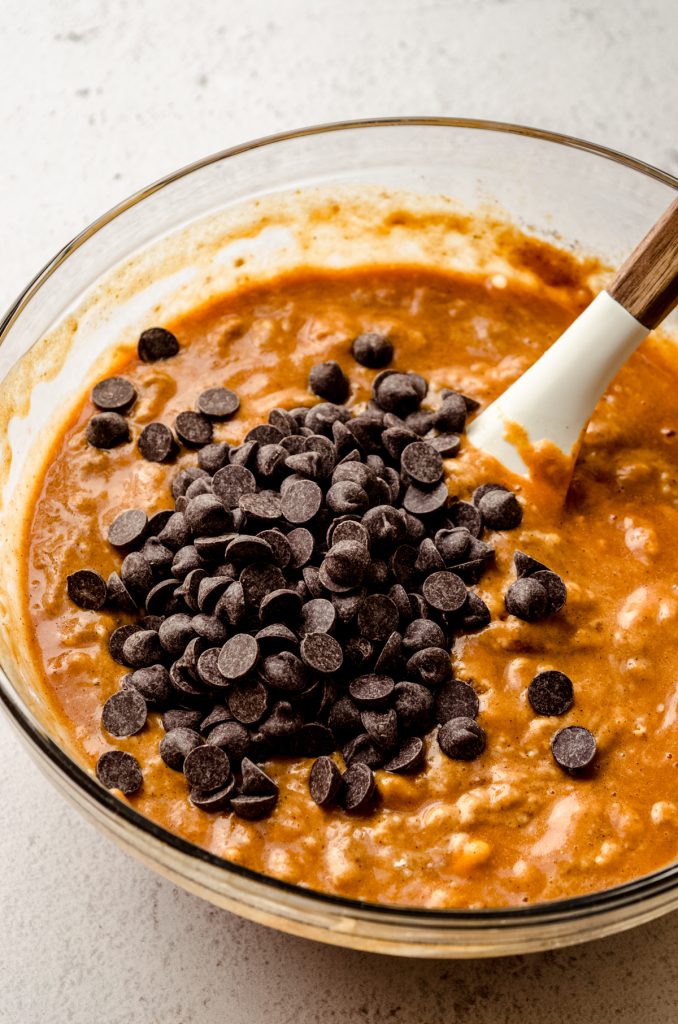 A bowl of pumpkin bread batter with chocolate chips in it.