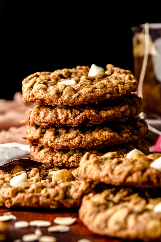 A stack of chai oatmeal cookies on a surface with a tea bag and a mug of chai in the background.
