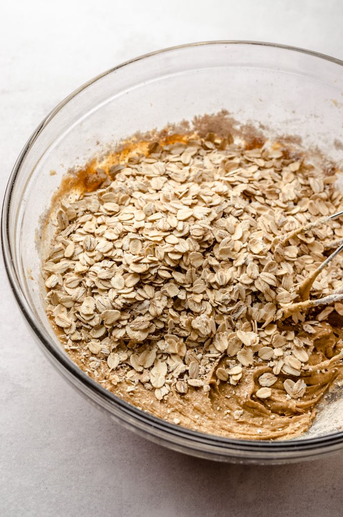 A bowl of ingredients to make chai oatmeal cookies with beaters in it.