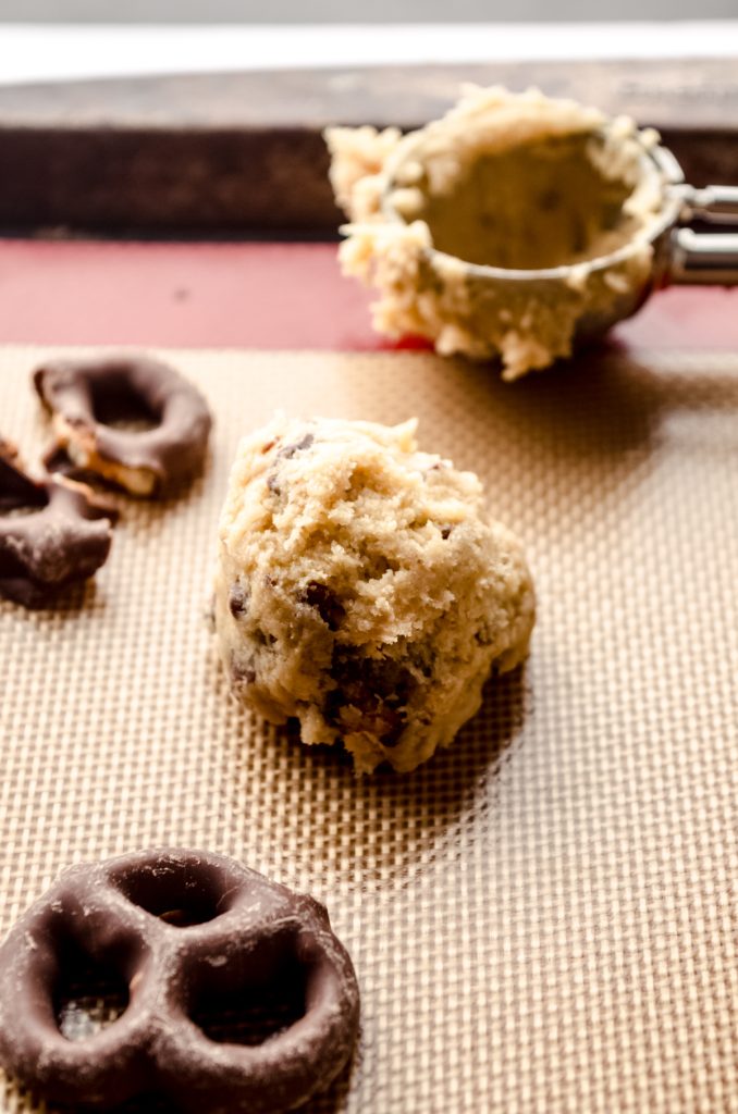 Chocolate covered pretzel cookie dough ball on a baking sheet.