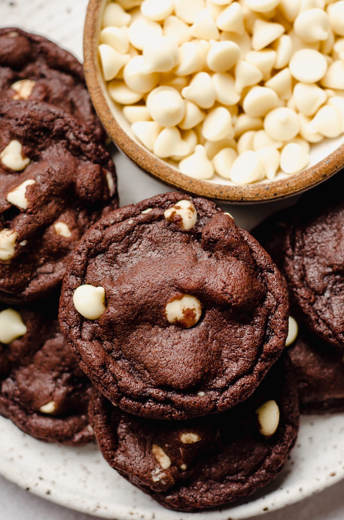 aerial photo of chocolate white chocolate chip cookies on a plate with a bowl of white chocolate chips