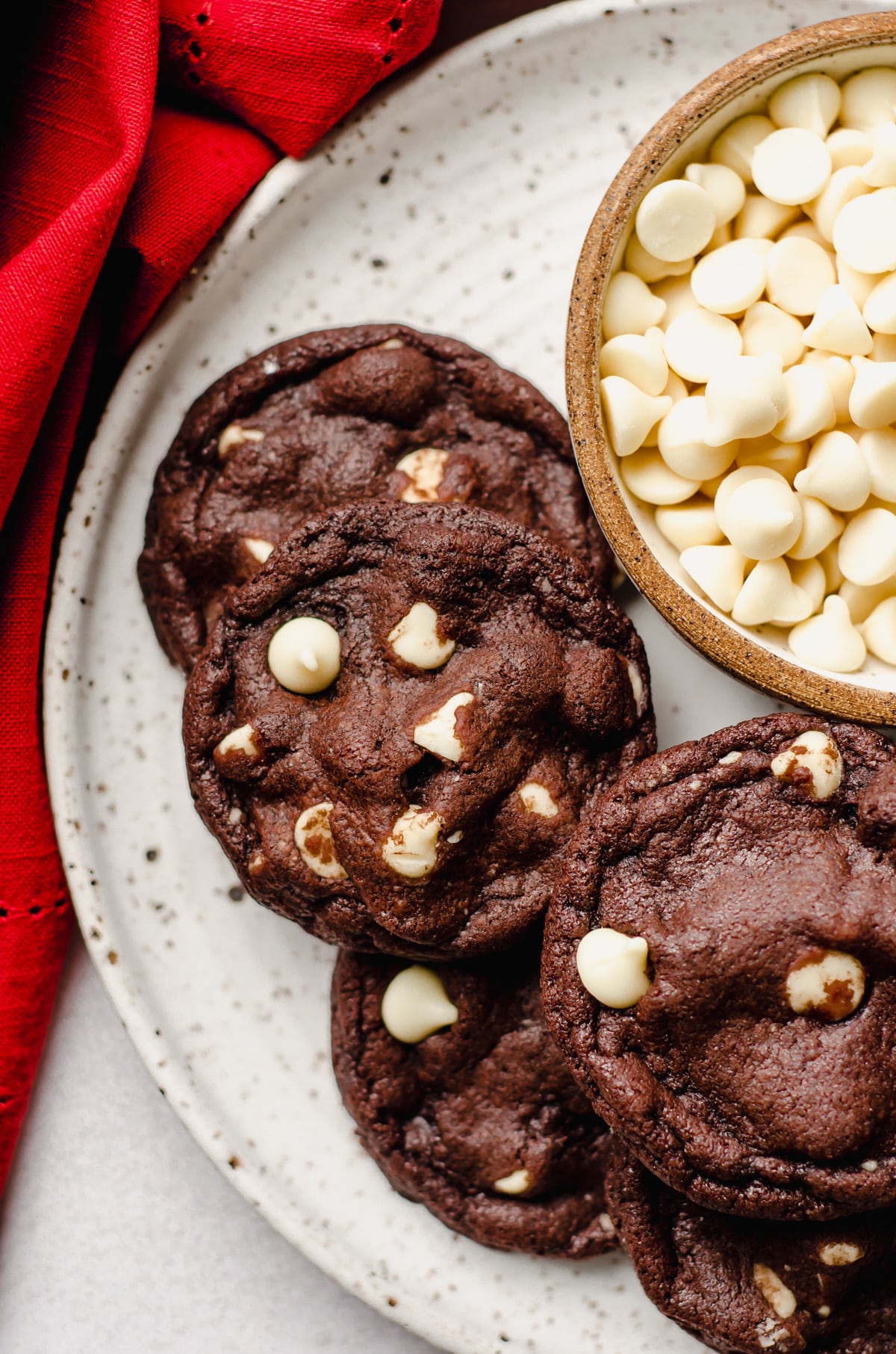 aerial photo of chocolate white chocolate chip cookies on a plate with a bowl of white chocolate chips