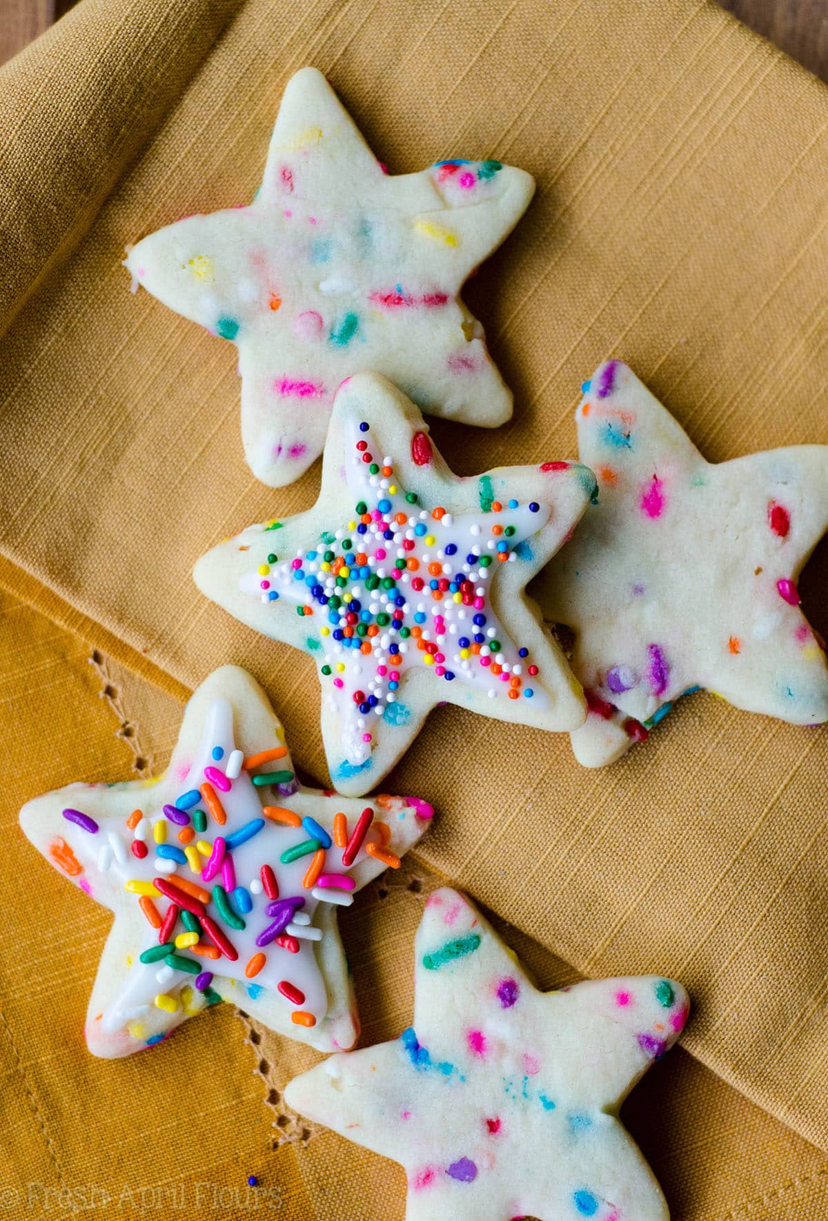 aerial photo of star shaped funfetti sugar cookies decorated with icing and rainbow sprinkles