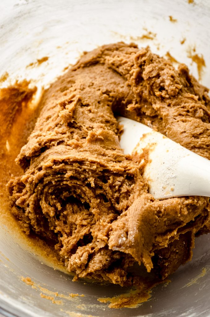 Gingerbread crinkle cookie dough in a bowl with a spatula.