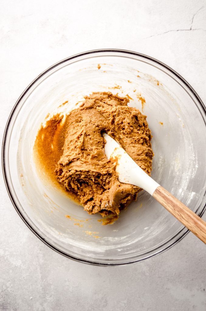 Gingerbread crinkle cookie dough in a bowl with a spatula.