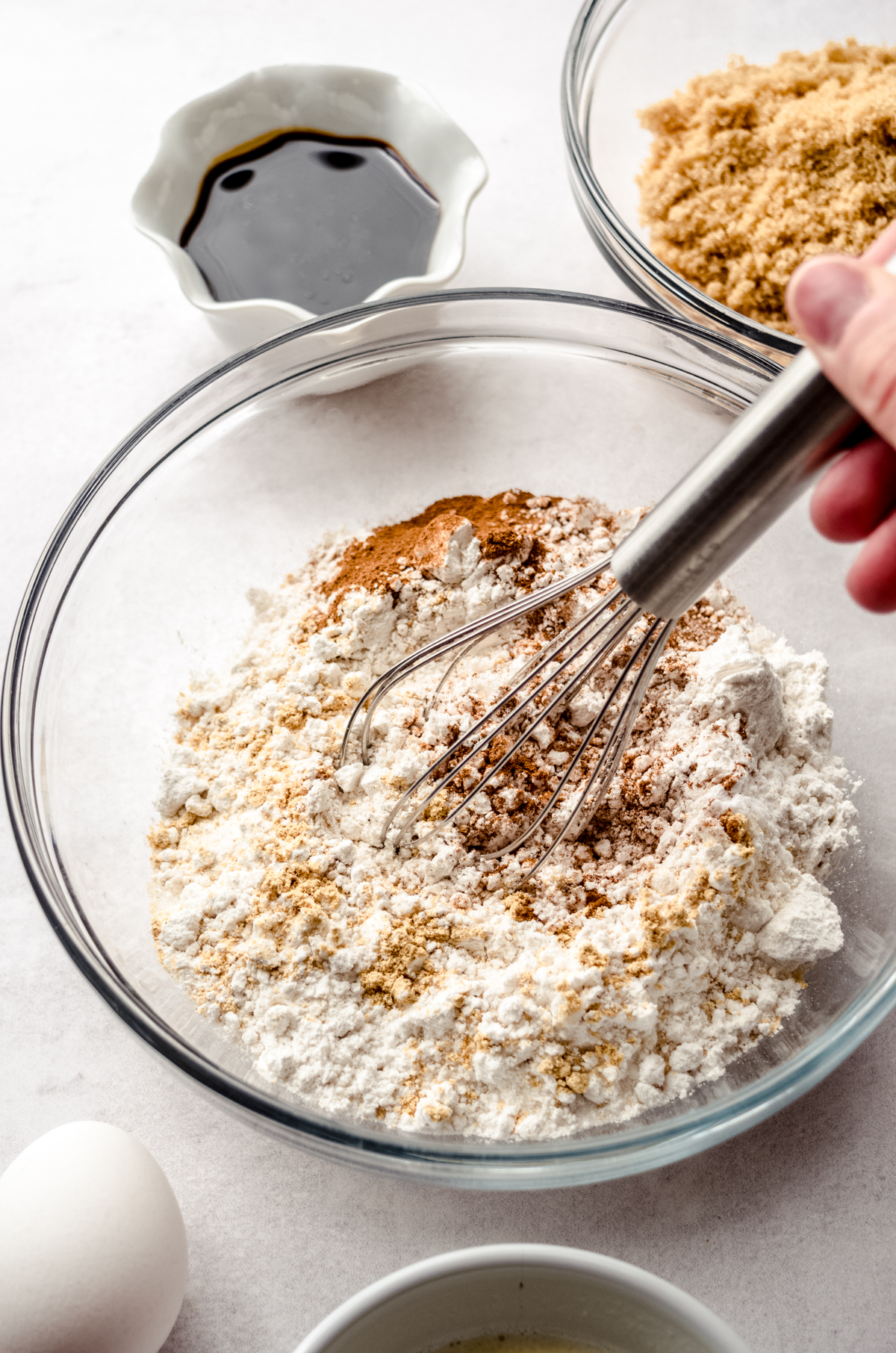 Someone is using a whisk to mix together the dry ingredients for gingerbread crinkle cookies.