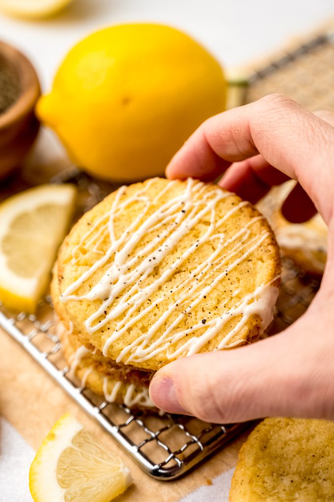 Someone is taking the top cookie off of a stack of lemon pepper cookies.