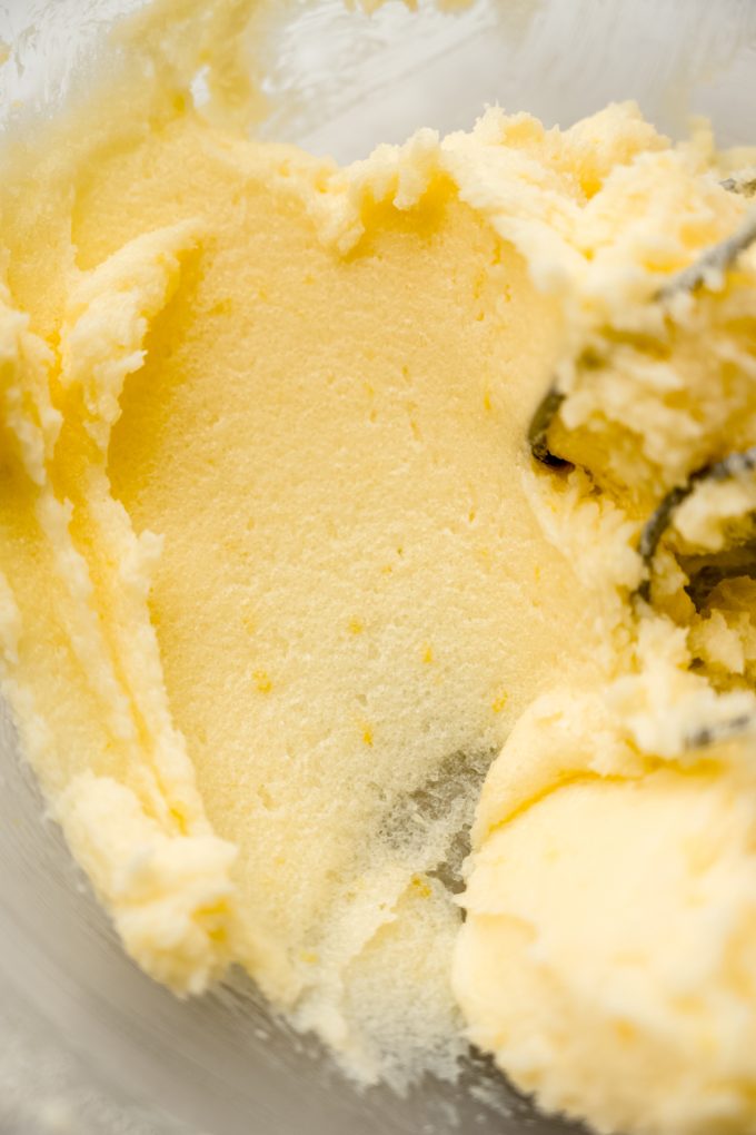 A bowl of creamed butter and sugar with lemon zest in it.