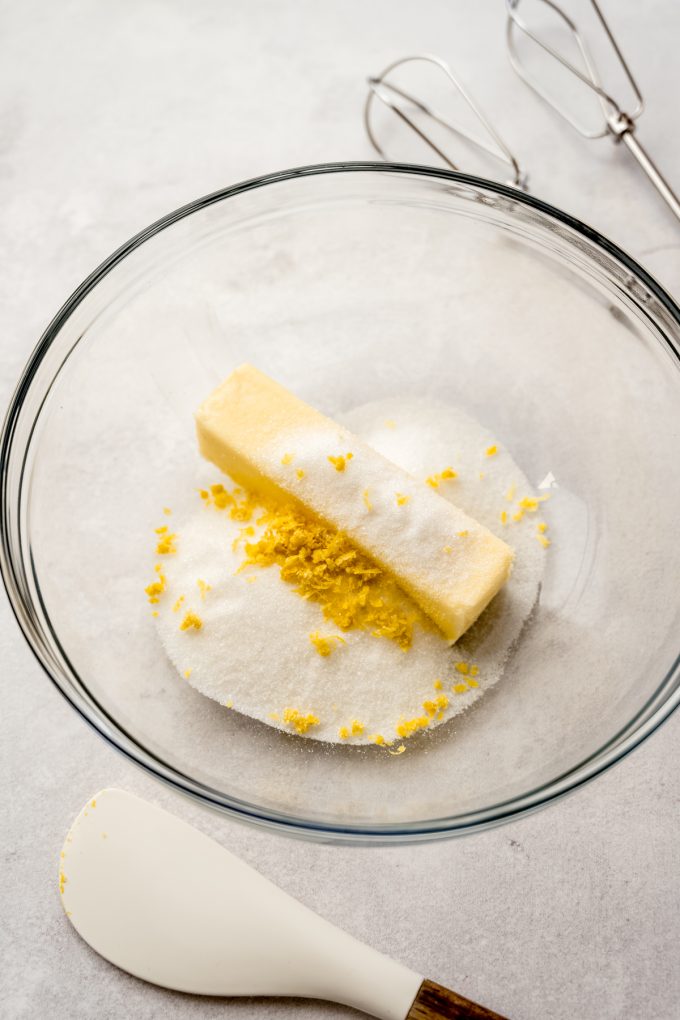 A glass bowl with sugar, butter, and lemon zest in it.