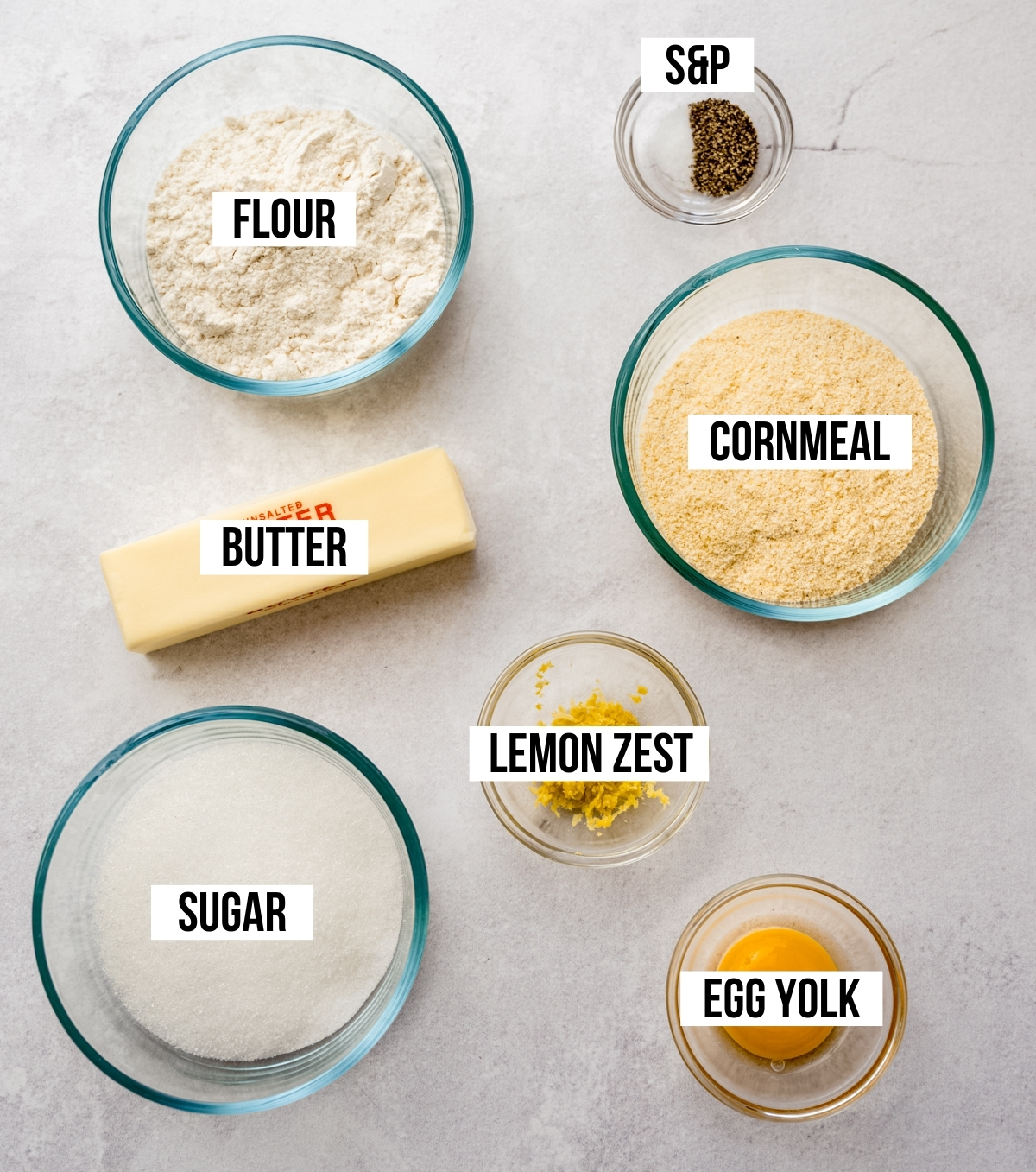 Aerial photo of ingredients to make lemon pepper cookies with text overlay labeling each ingredient.