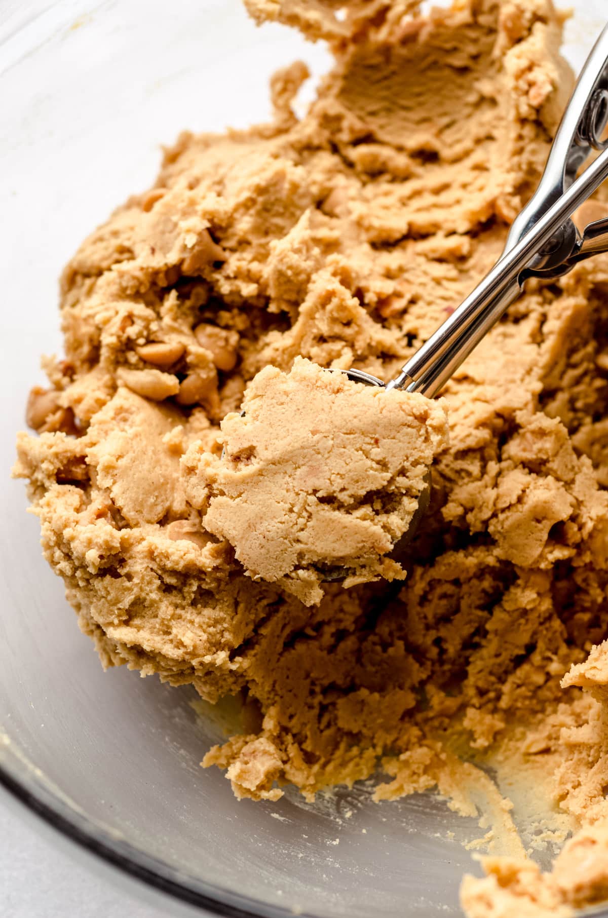 peanut butter cookie dough in a bowl with a cookie scoop