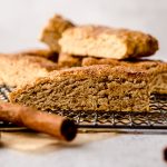 Snickerdoodle biscotti on a wire cooling rack with cinnamon sticks around it.