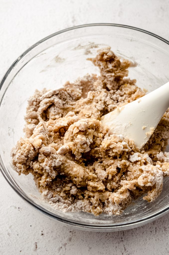 Dry ingredients and some wet ingredients in a bowl to make biscotti getting mixed together with a large spatula.