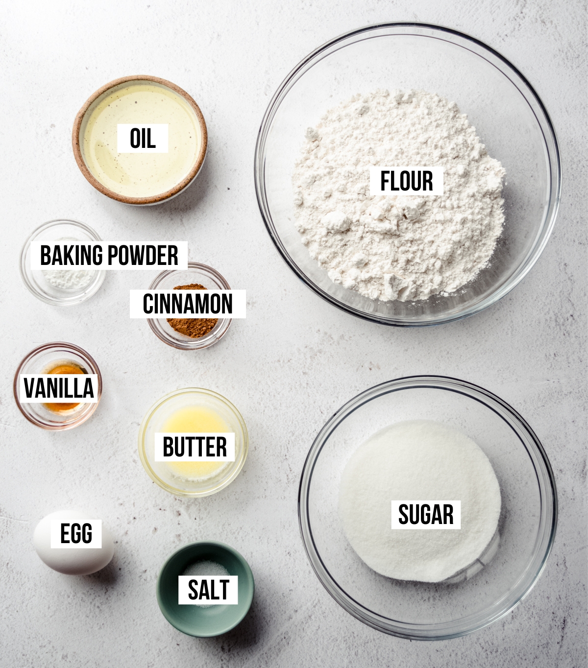 Aerial photo of ingredients to make snickerdoodle biscotti with text overlay labeling each ingredient.