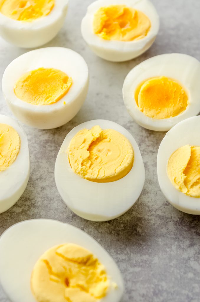 Hard cooked eggs cut in half on a surface to reveal the inside doneness of the yolks.