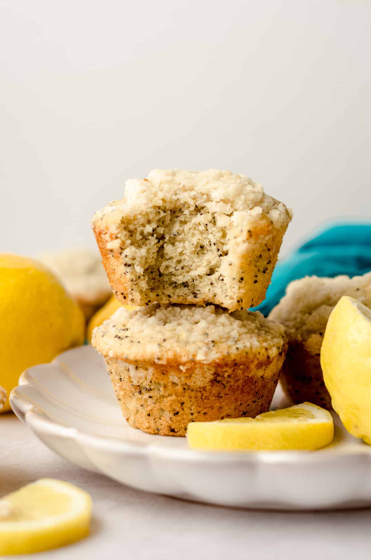 stack of two lemon poppy seed muffins with the on the top with a bite taken out of it