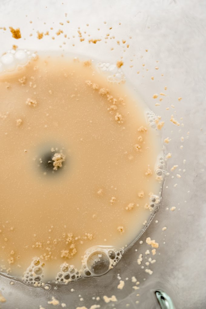 A yeast mixture in the bottom of a mixing bowl.