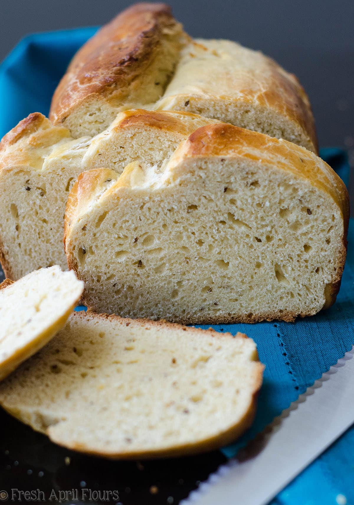 loaf of anise bread sliced and on a blue kitchen towel 