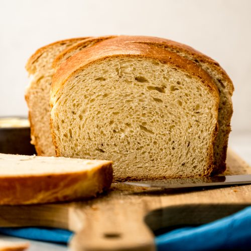 A photo of a sliced loaf of anise bread on a cutting board.