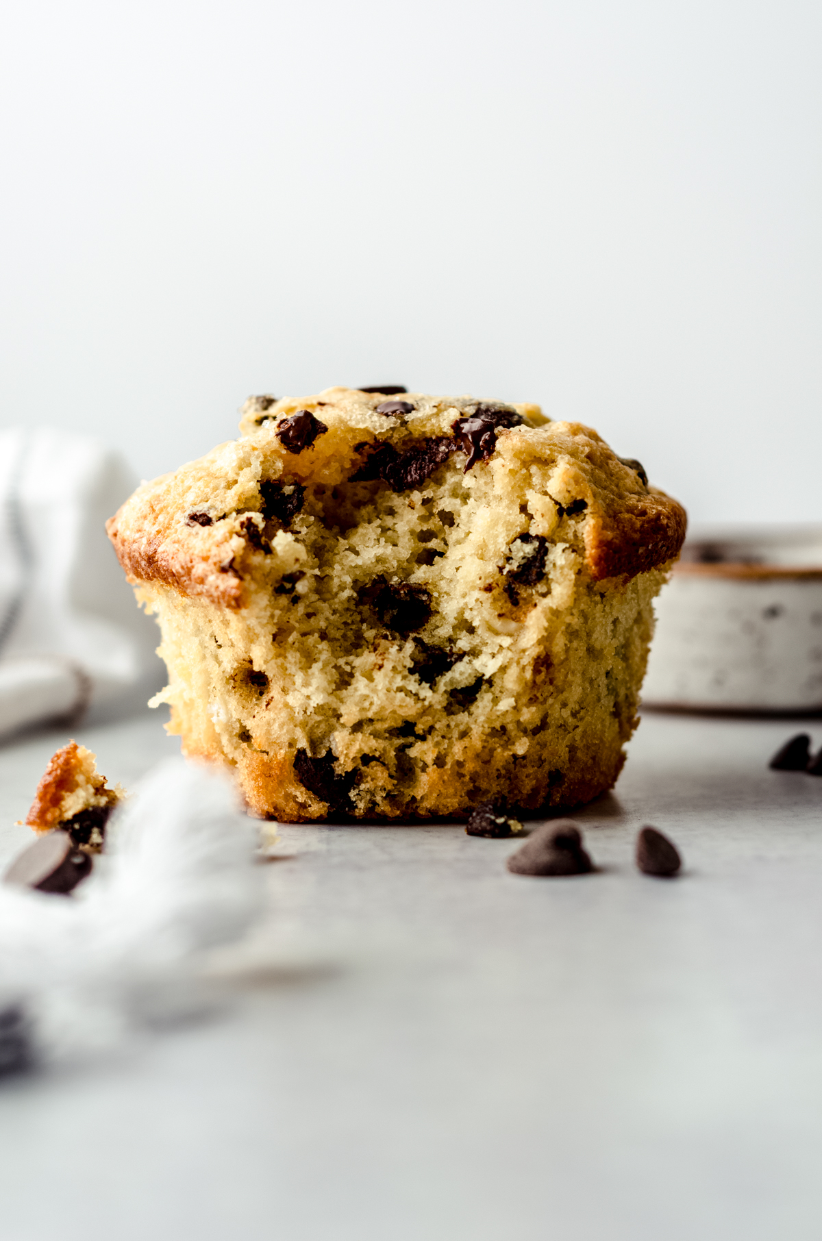 A chocolate chip muffin with a bite taken out of it.