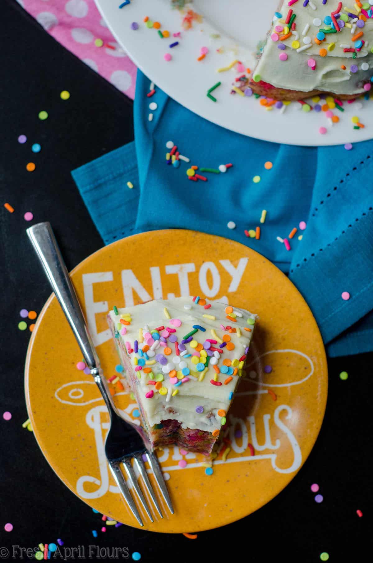 aerial photo of a slice of funfetti bundt cake on a plate with sprinkles
