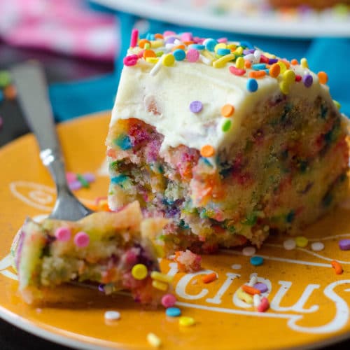 slice of funfetti bundt cake with a bite taken out of it on a plate with sprinkles