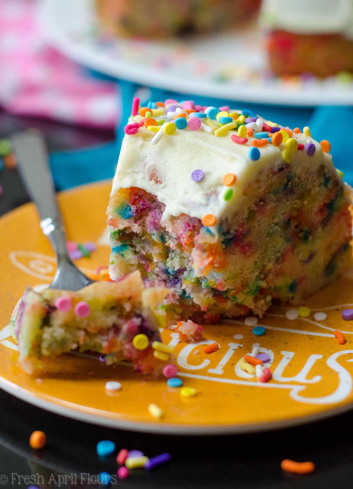 slice of funfetti bundt cake with a bite taken out of it on a plate with sprinkles