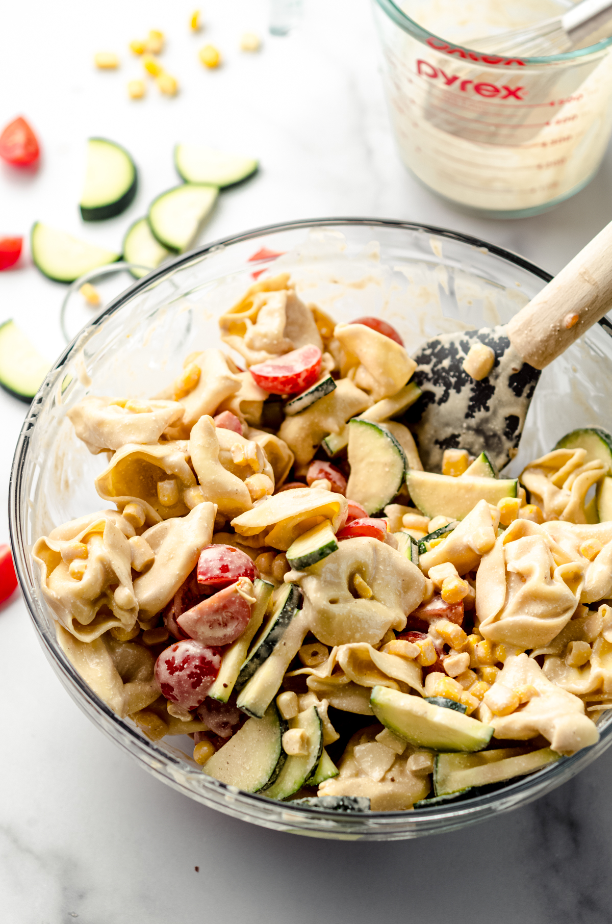 Tortellini pasta salad in a bowl with a spatula.