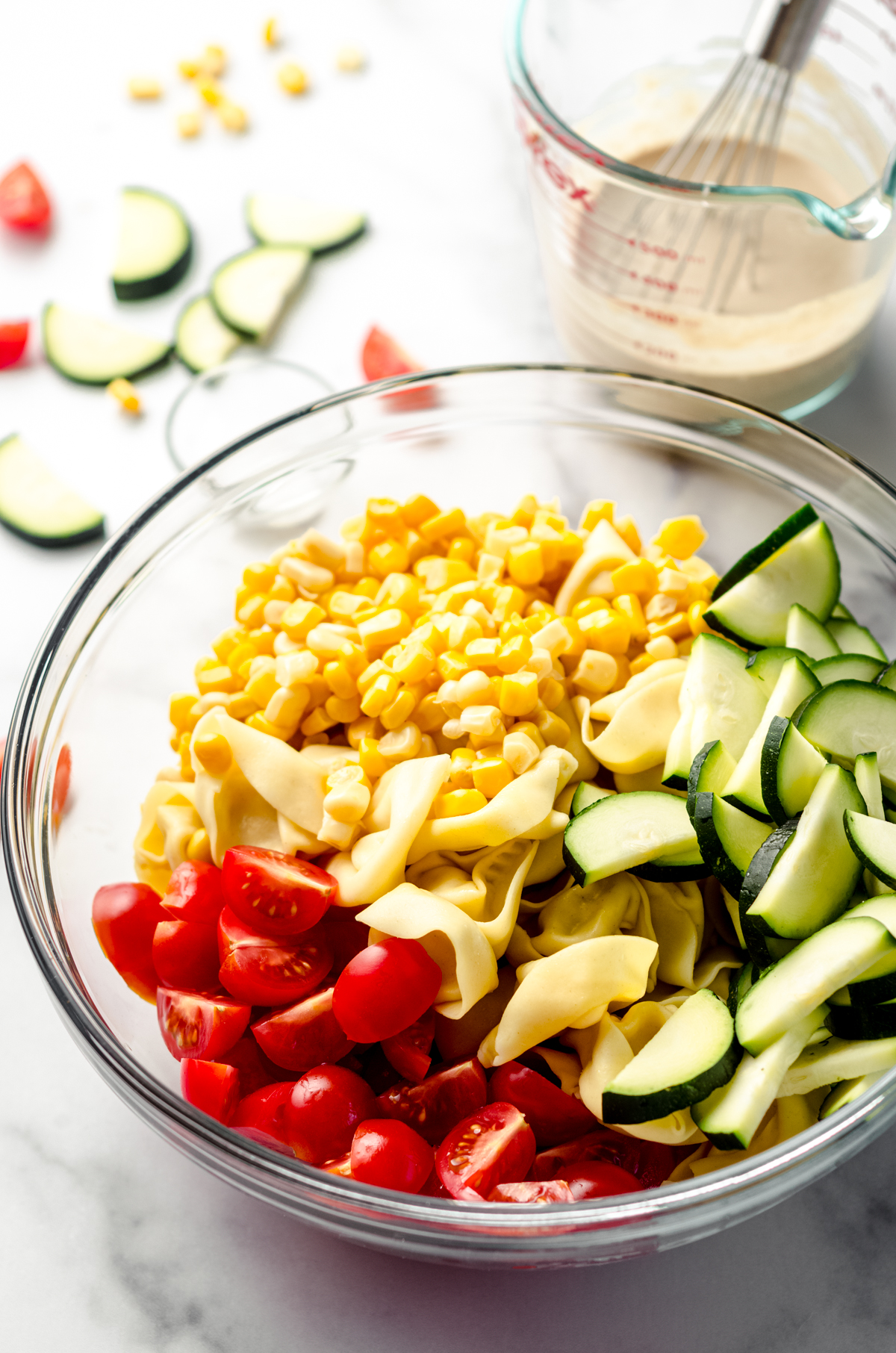 A bowl of vegetables and tortellini pasta for summer pasta salad.