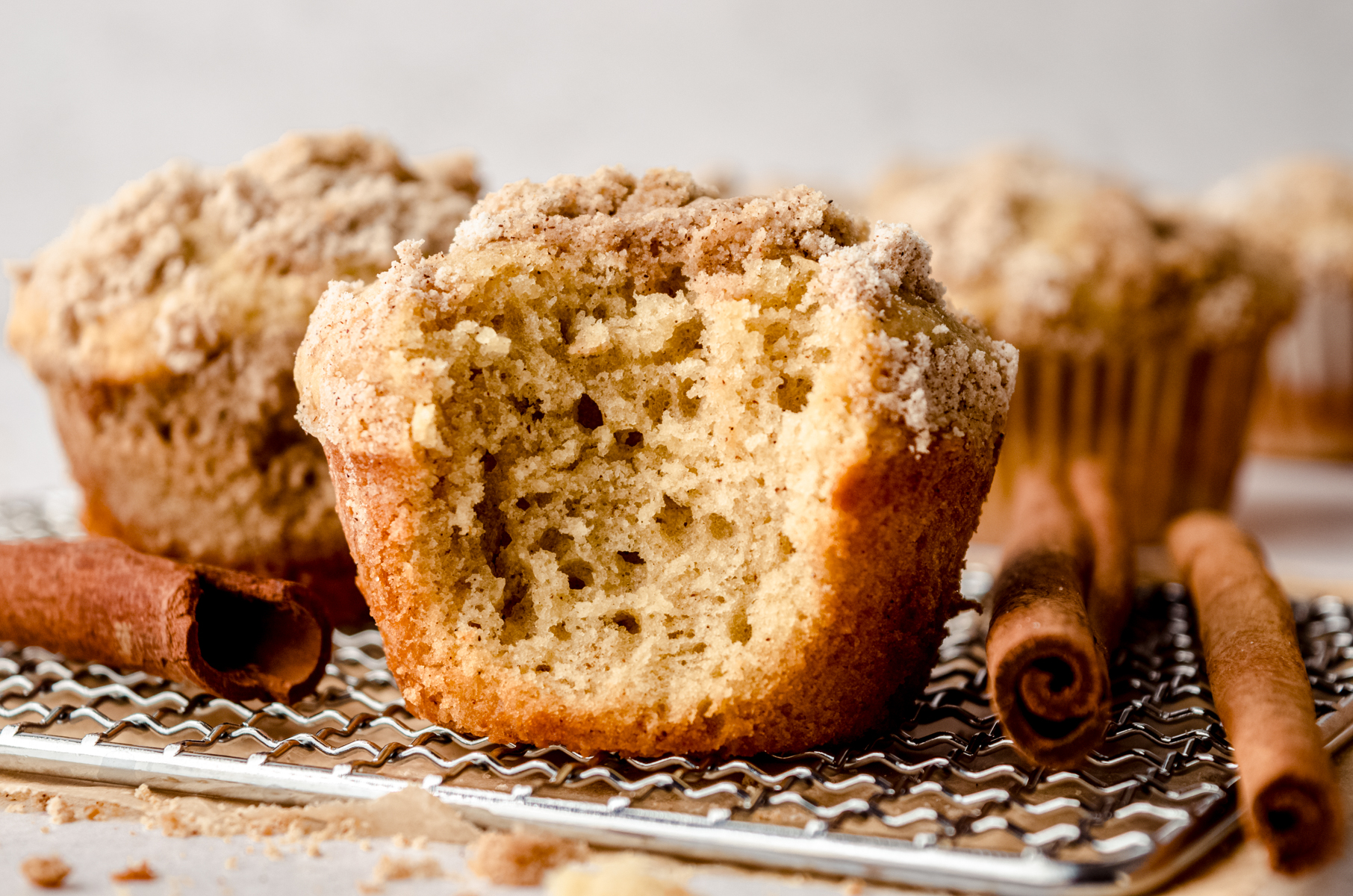 A coffee cake muffin with a bite taken out of it on a wire cooling rack.